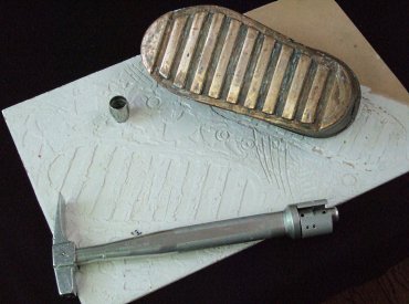 A bronzed spacesuit boot print, a geological core sample tube and rock hammer Bean used during his lunar mission.