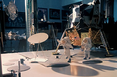 A mockup of two astronauts on the lunar surface standing in front of the lunar lander. One of them is throwing a piece of foil into the air.